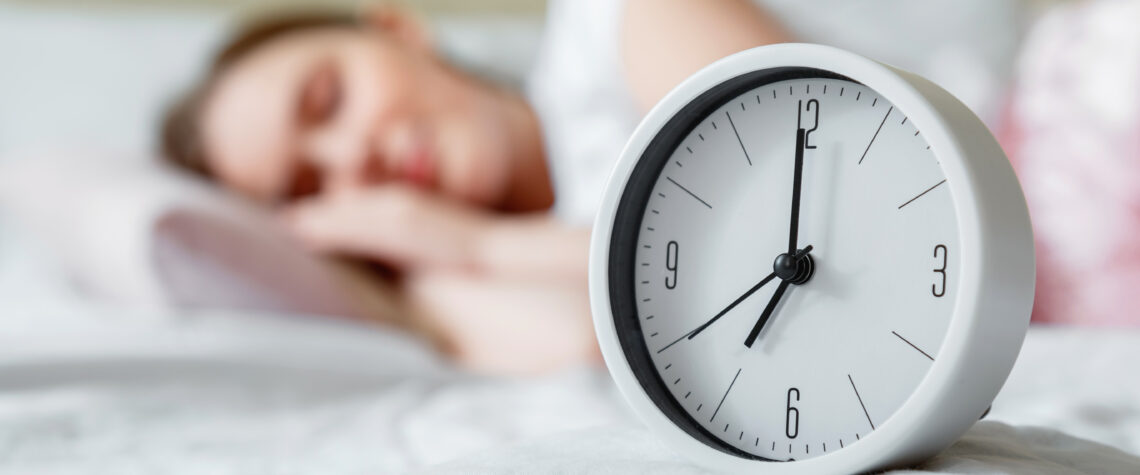 Alarm clock resting on bed while woman sleeps | Nashville Christian Family Magazine - Free Christian Magazine
