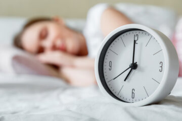Alarm clock resting on bed while woman sleeps | Nashville Christian Family Magazine - Free Christian Magazine
