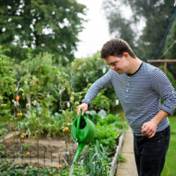 Adult man with Down Syndrome watering plants Free Issue of the Nashville Christian Family magazine - Free Christian Magazine