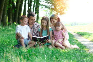 Make This Easter Memorable - Young and Happy Family with Children reading the Bible outside | April 2023 issue \ Nashville Christian Family Magazine
