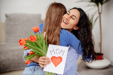 Honoring Mom on Mother's Day - Child Daughter Congratulates Mom And Gives Her Flowers Tulips | Nashville Christian Family Magazine - May 2023 issue - Free Christian Magazine