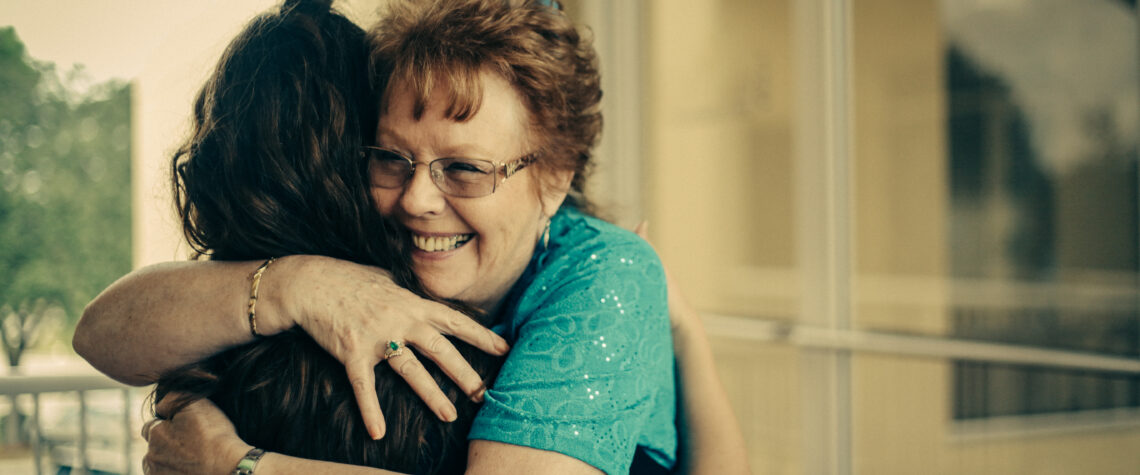 Mature woman smiling and hugging a younger women | Nashville Christian Family Magazine