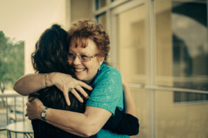 Mature woman smiling and hugging a younger women | Nashville Christian Family Magazine