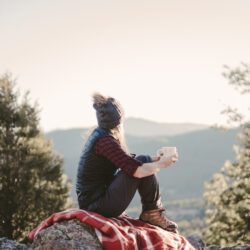 Discovering Healthy Self-Love as a Christian Entrepreneur - Body and Soul - woman sitting on blanket on a rock with cup in her hand as she gazes across the valley | Nashville Christian Family Magazine