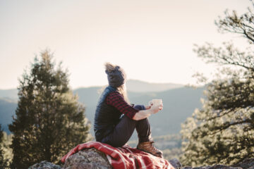 Body and Soul - woman sitting on blanket on a rock with cup in her hand as she gazes across the valley | Nashville Christian Family Magazine